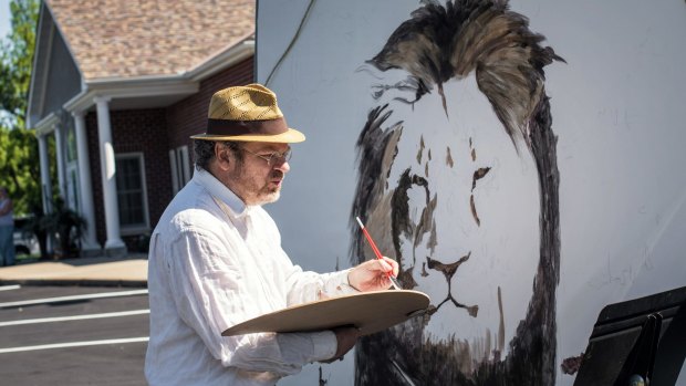 Artist Mark Balma paints a mural of Cecil outside Walter Palmer's office in Bloomington, Minnesota.