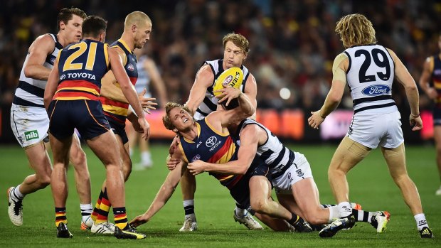 Rory Sloane of the Crows tries to dispose of the ball as  he is tackled.