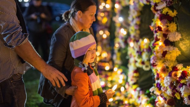 A young girl is guided to place a candle on a flower wall that reads "#keephopealive" as part of an Amnesty international vigil for the Bali nine duo, Andrew Chan and Myuran Sukumaran.