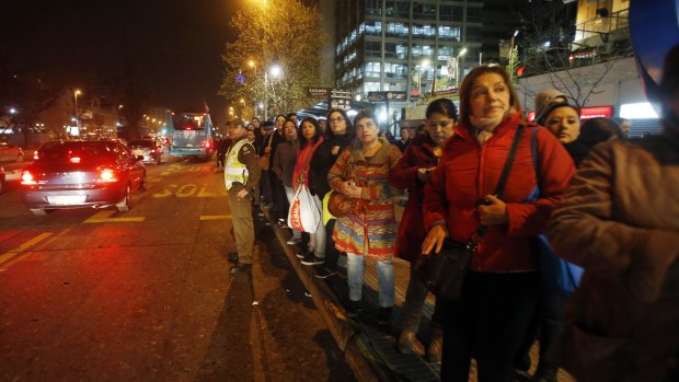 A police officer stands in the street to flag down buses to take people home after a powerful earthquake hit Chile's northern coast.