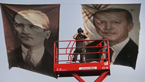 A Turkish police officer at a rally of the ruling AK Party in May is flanked by posters of the Turkish republic's founder, Mustafa Kemal "Ataturk", left, and Turkish President Recep Tayyip Erdogan.