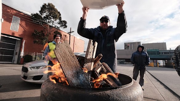 Sacked workers try to keep warm on the picket line.