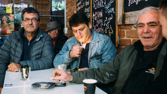 Niko Penesis (from left), Kostas Dotas and Spiros Psiroyiannis enjoy a morning smoke and coffee at Kentro in Eaton Mall. 