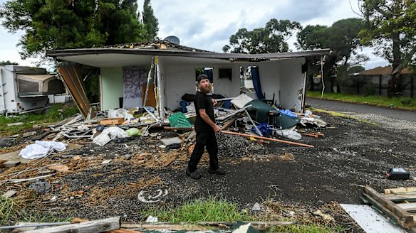 Hobsons Bay Caravan Park resident Michael walks past a trashed van that belonged to his neighbour. 