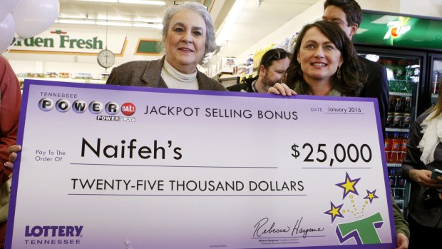 Rebecca Hargrove, left, president & CEO of the Tennessee Lottery, presents a check to Dana Naifeh, right, owner of Naifeh's Grocery in Munford, Tennessee where John Robinson bought the winning Powerball ticket.
