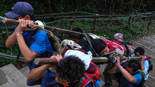 Members of a Malaysian rescue team carry an injured Singaporean student after an earthquake in Kundasang, a town in the district of Ranau.