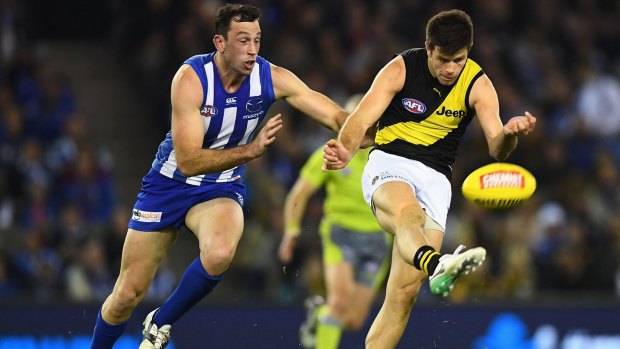 Richmond skipper Trent Cotchin gets his kick away as Roo ruckman Todd Goldstein gives chase.