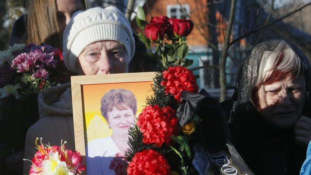A mourner holds a portrait of Nina Lushchenko, one of the victims of a plane crash, at her funeral at a cemetery in the village of Sitnya in Russia on Thursday. 
