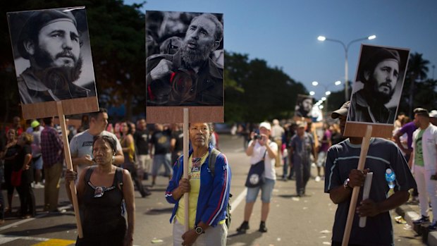 Mourners hold pictures of Fidel Castro as they wait to pay their last respects in Havana on Monday.