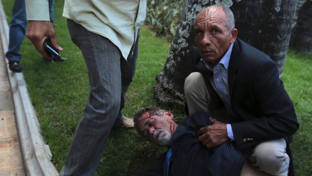A bodyguard watches over opposition lawmaker Americo De Grazia, who was injured in a melee with pro-government militia members.