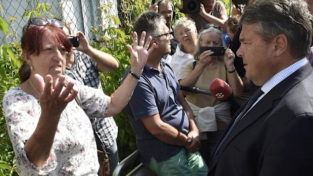 Germany's deputy chancellor and Social Democratic Party leader Sigmar Gabriel talks to a resident after visiting accommodation for  asylum seekers in the eastern German gown of Heidenau. 