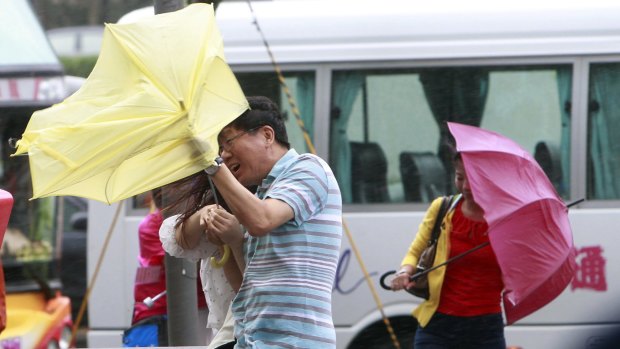 Tourists struggle in wild winds as Typhoon Dujuan nears Taipei on Monday.