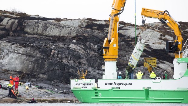 Air disaster: A recovery vessel lifts up parts of a crashed helicopter from off the island of Turoey, near Bergen, Norway, on Friday.