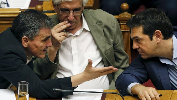 Greek Prime Minister Alexis Tsipras, right, listens to Finance Minister Euclid Tsakalotos as Justice Minister Nikos Paraskevopoulos, centre, looks on during a parliamentary session in Athens on Thursday. 