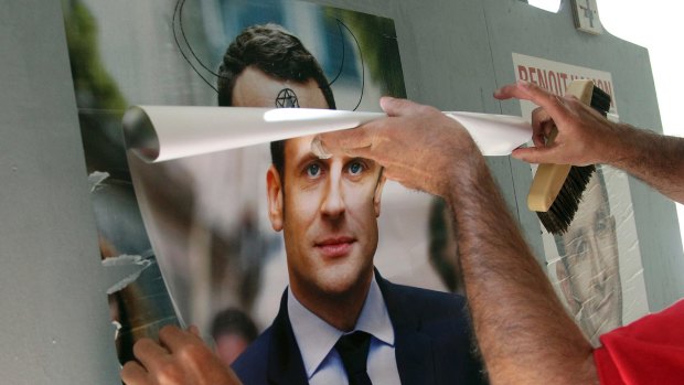 Christophe Sanz, a supporter French centrist presidential candidate Emmanuel Macron, sticks a campaign poster in Bayonne, south-western France.