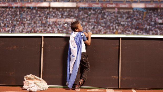 A young Honduras fan wears a Honduras national flag as a cape during a World Cup qualifying soccer match in San Pedro Sula.
