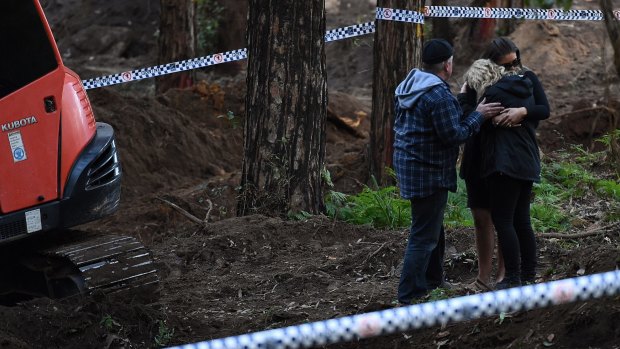 Faye Leveson (centre) is comforted by a family friend and her husband Mark Leveson (left) at the edge of the crime scene where human remains were unearthed.