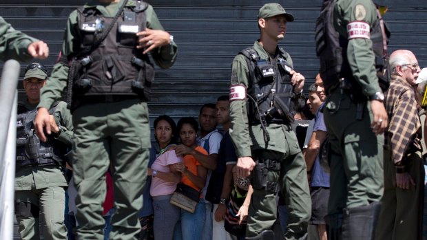 Locals are surrounded by Venezuelan Bolivarian National Guards officers as they line up outside a supermarket to buy food at discounted prices, in Caracas, last week.