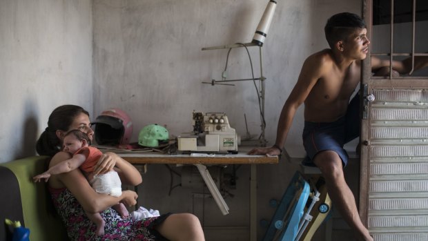 Angelica Pereira, left, holds her daughter Luiza near her husband Dejailson Arruda at their home in Santa Cruz do Capibaribe, Pernambuco, Brazil. Luiza was born in October with the rare condition microcephaly.