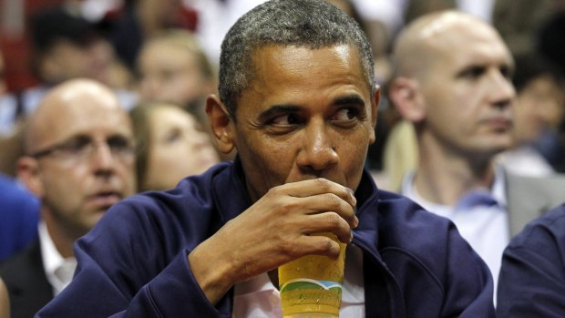 Preseident Barack Obama enjoys a beer as he watches a basketball game.