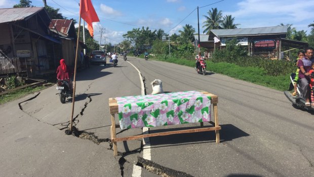 A table and flag warn motorists of cracks in the road in Trienggadang, Aceh.