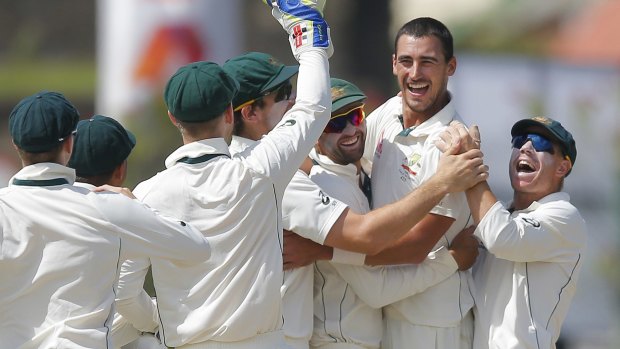 Australia's Mitchell Starc celebrates with teammates after taking a wicket with the first ball.