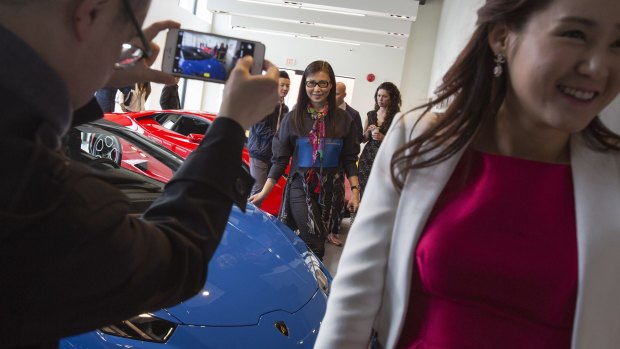 Paul Oei photographs his wife Loretta Lai, centre, with a new car at a Lamborghini dealership reception in Vancouver.