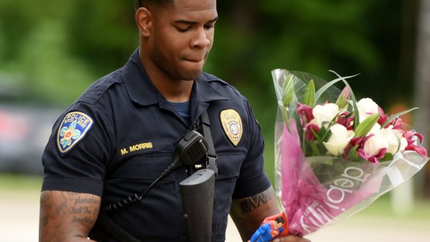 Baton Rouge Police Department Officer Markell Morris holds a bouquet of flowers and a Superman at the Our Lady of the Lake Hospital where shot police officers were taken.