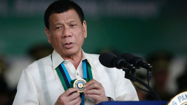 Philippine President Rodrigo Duterte shows a medal during his speech to troops in Quezon City in December.