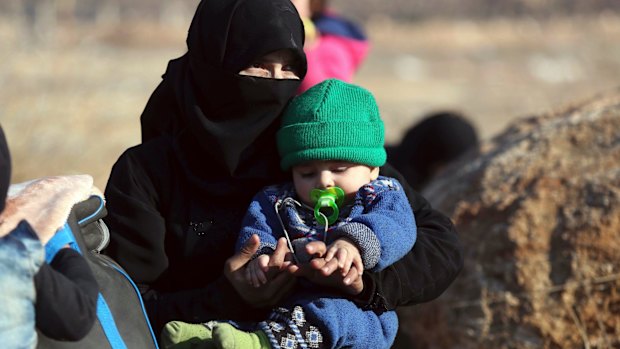 A Syrian woman holds a child at the refugee camp. 