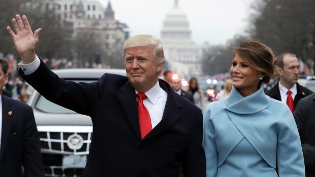 President Donald Trump waves as he walks with first lady Melania Trump during the inauguration parade on Pennsylvania Avenue.