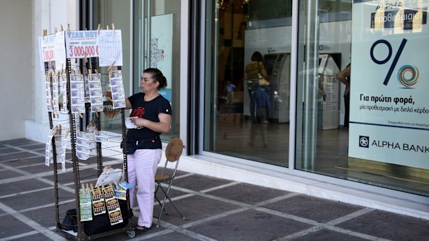 A vendor sells lottery tickets outside a bank in Athens on Friday. More discussions over Greece's third bailout in five years are set to begin in Athens imminently.