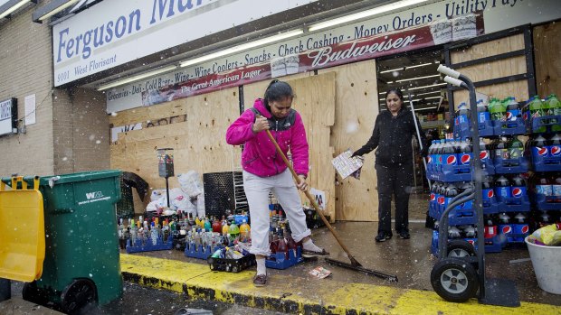 Victim of unrest: Anjana Patel cleans up damage to her shop  in Ferguson.