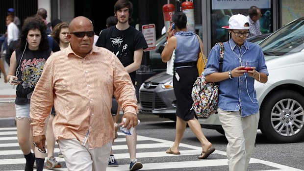 A pedestrian texts while crossing the street in downtown Washington. 