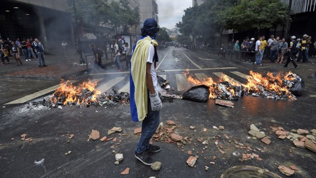 An opponent of Venezuelan President Nicolas Maduro stands in front of a flaming barricade in Caracas.