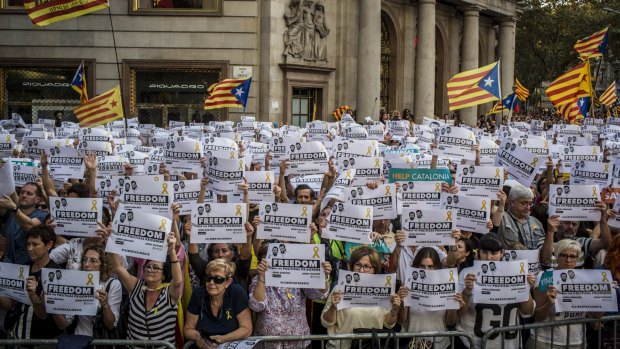 Protesters wave Catalan flags, also known as the Senyera, and hold signs during a demonstration against the Spanish government.