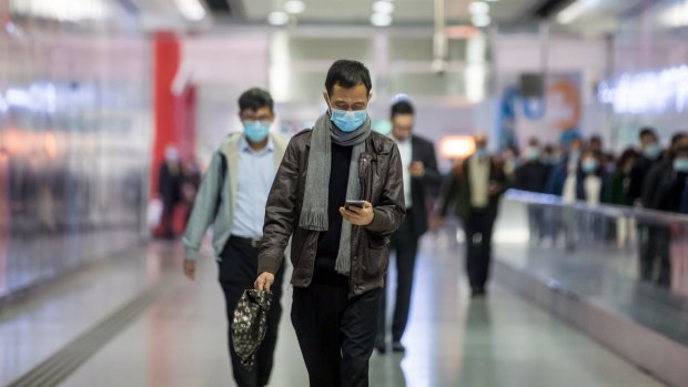 Commuters wearing protective masks walk through Hong Kong Station.