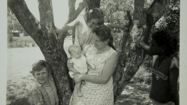 Then nursing sister Mary Porter in the early 1970s in the Northern Territory with a young Aboriginal boy and her children Geoffrey, now 50, Daniel, now 42, and Lesley, now 46.