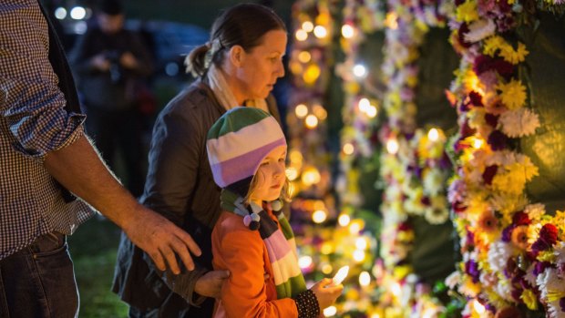 A young girl is guided to place a candle as part of an Amnesty international vigil.