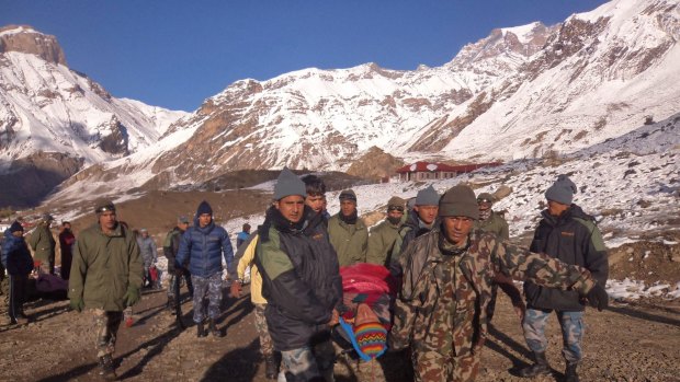 An injured hiker is assisted by Nepal Army soldiers in Manang District, along the Annapurna Circuit hiking trail. A snowstorm and avalanche in Nepal's Himalayas has killed 17 trekkers and guides. More than 100 people are still missing.