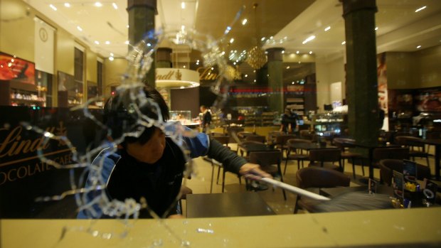 A man cleans up broken glass from vandalised windows at the Lindt cafe in Martin Place, Sydney.