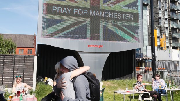 A couple embrace under a billboard in Manchester city centre on Tuesday.