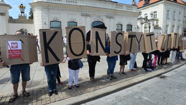 People hold boards with the word "Constitution" in front of the presidential palace Warsaw, Poland, July 24, 2017.