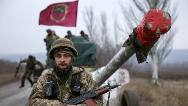 A Ukrainian soldier stands guard as a convoy prepares to pull back from the Debaltseve region.