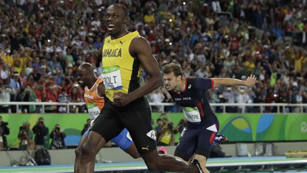 Usain Bolt smiles as he crosses the line.