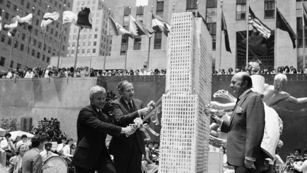 Rockefeller, second left, assists in slicing up a culinary replica of the Rockefeller Centre in New York on the building's 50th birthday in 1982.
