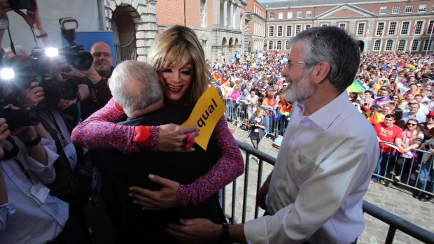 Drag queen and gay rights activist, Rory O'Neill (centre) hugs Senator David Norris with Sinn Fein president Gerry Adams looking on at Dublin Castle as they wait for the result of the referendum on Saturday.