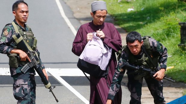 Government troops frisk a Muslim man at a checkpoint leading to Marawi city three days after Muslim militants lay siege in the city in southern Philippines.