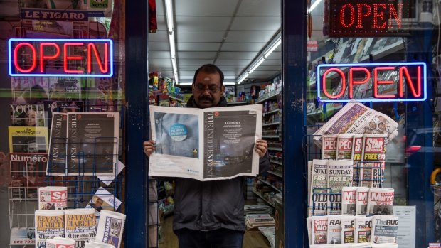 A newsagent reads the final print edition of The Independent on Sunday outside his shop in Soho on March 20.