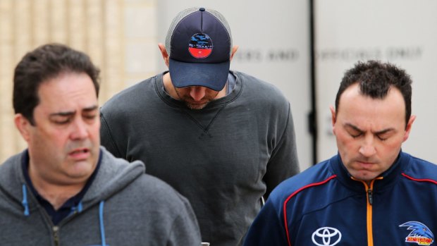 James Podsiadly (centre) leaves the Crows club rooms.